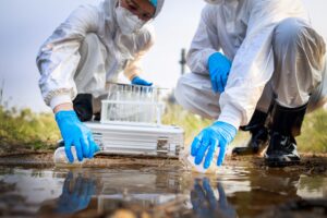 Two Scientists in protective suits and masks took a sample of water for analysis